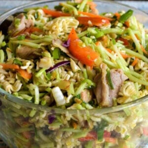 Asian ramen broccoli coleslaw with bits of cooked chicken and matchstick pieces of red bell pepper.