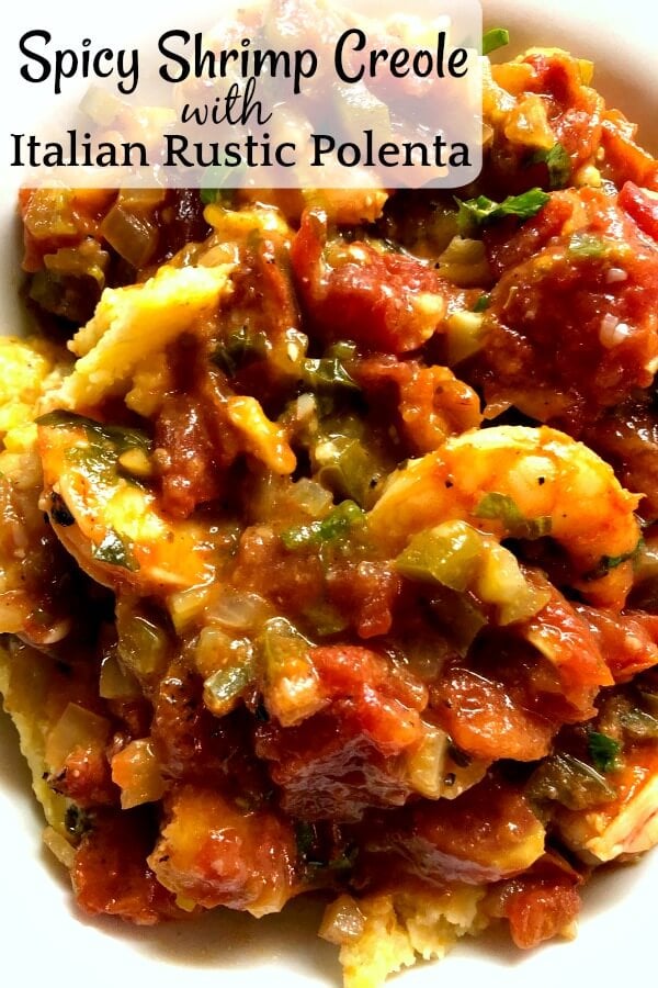 A closeup of a bowlful of shrimp creole on top of golden polenta. 