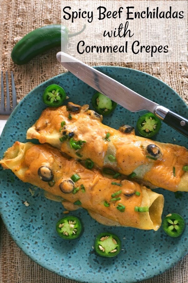 Two beef enchiladas on a aqua speckled plate with jalapeño slices on the plate. 