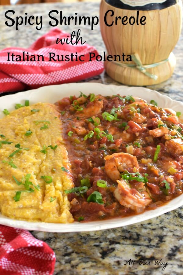 White bowl holds polenta and shrimp creole in tomato sauce with a red striped tea towel and a bottle of chianti wine. 