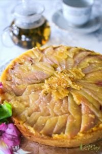 Upside down pear polenta cake with a carafe of tea and a tea cup .