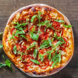 Pizza with cheese, red sauce and green arugula topping.