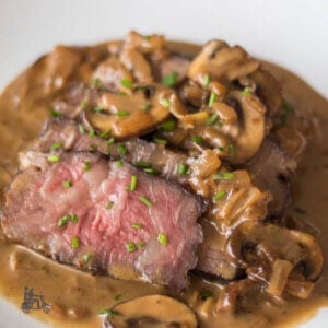Steak Diane with mushroom sauce on a white china plate.