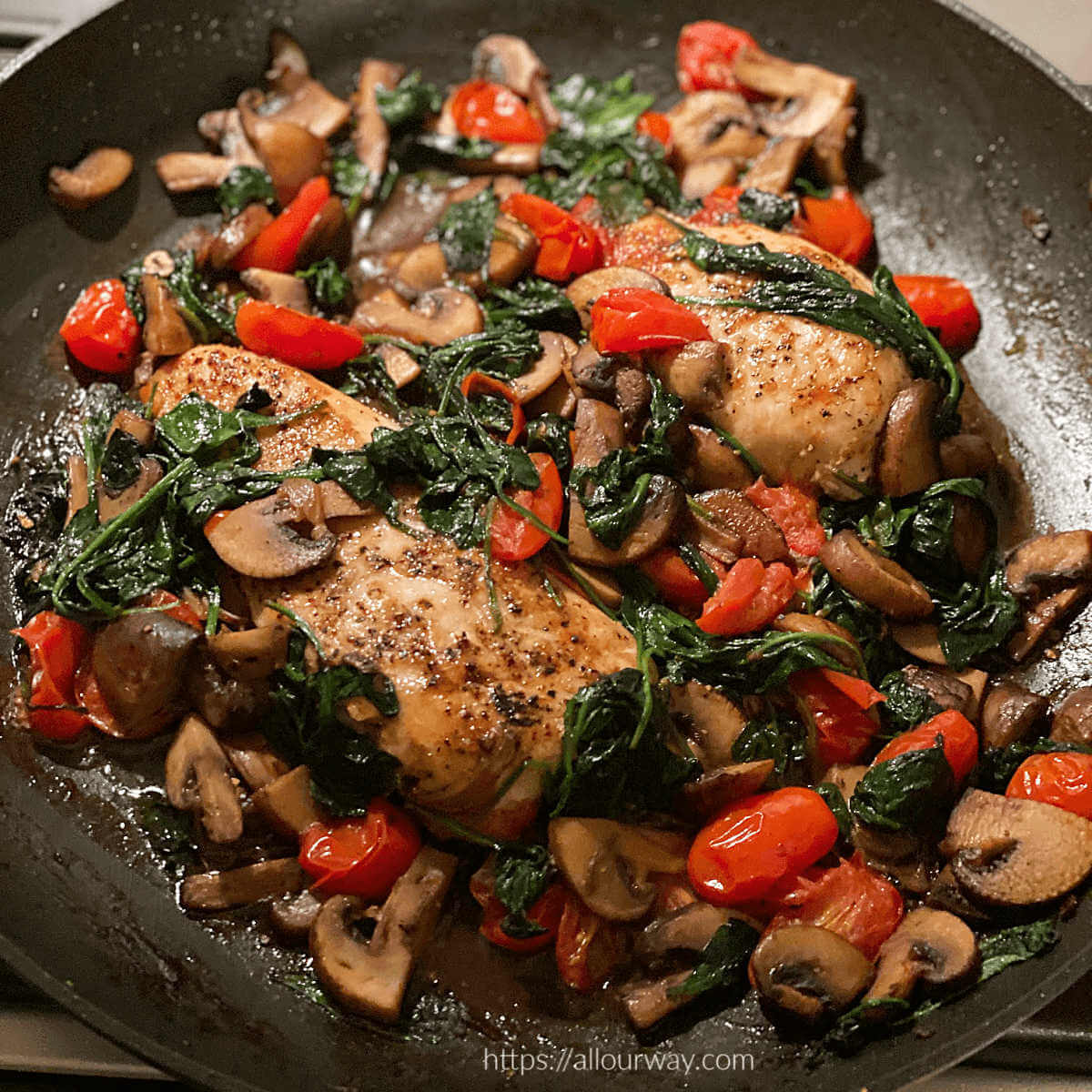 Chicken Florentine in skillet made with fresh spinach and halved grape tomatoes. 