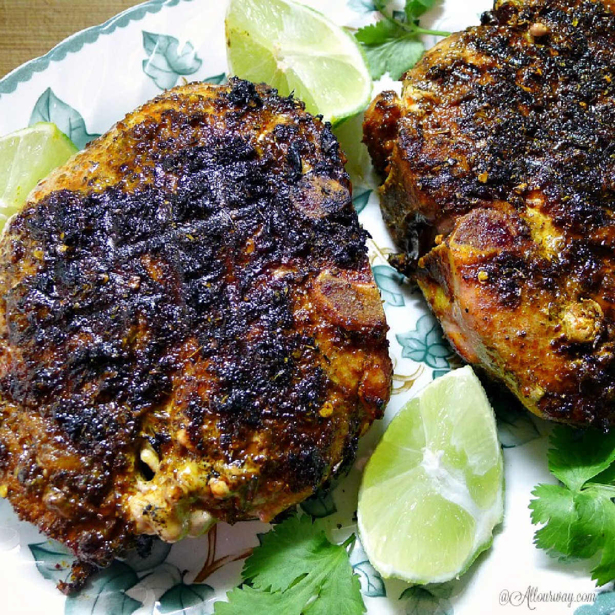 Grilled Lime Adobo Rubbed Pork Chops have the flavor of Mexico with lime on green leaf platter.
