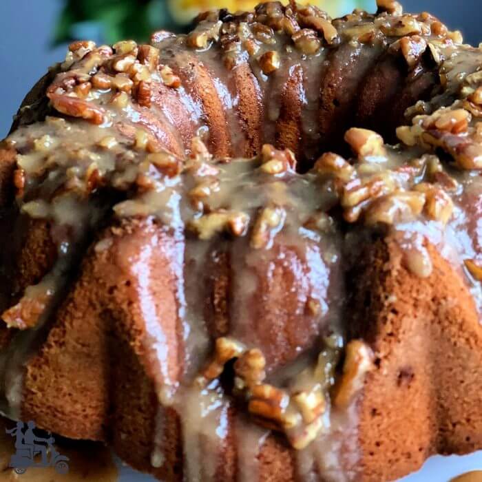 Closeup of Praline Pecan Bundt Cake with a caramel glaze and topped with pecans. 