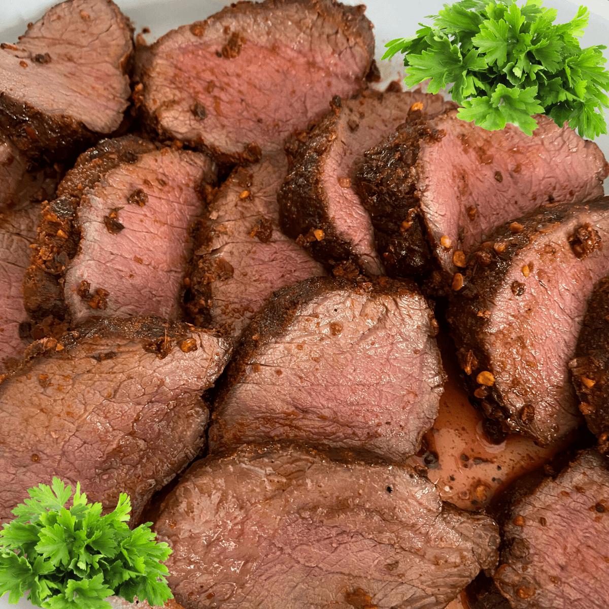 Grilled venison backstrap sliced with parsley on side. 