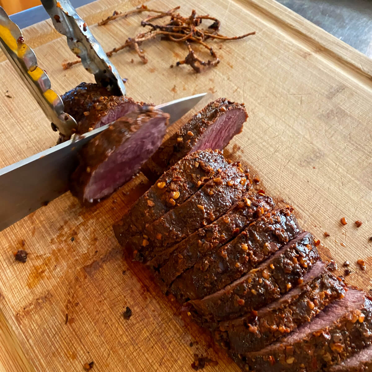 Venison Backstrap on cutting board being sliced. 
