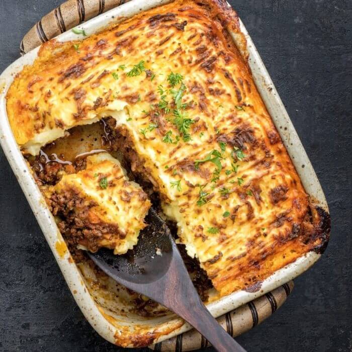 Casserole with mashed potatoes on top of meat filling. Shepherds Pie with spoon taking out a portion. 