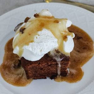 Persimmon pudding with whipped cream and a caramel pecan sauce over it