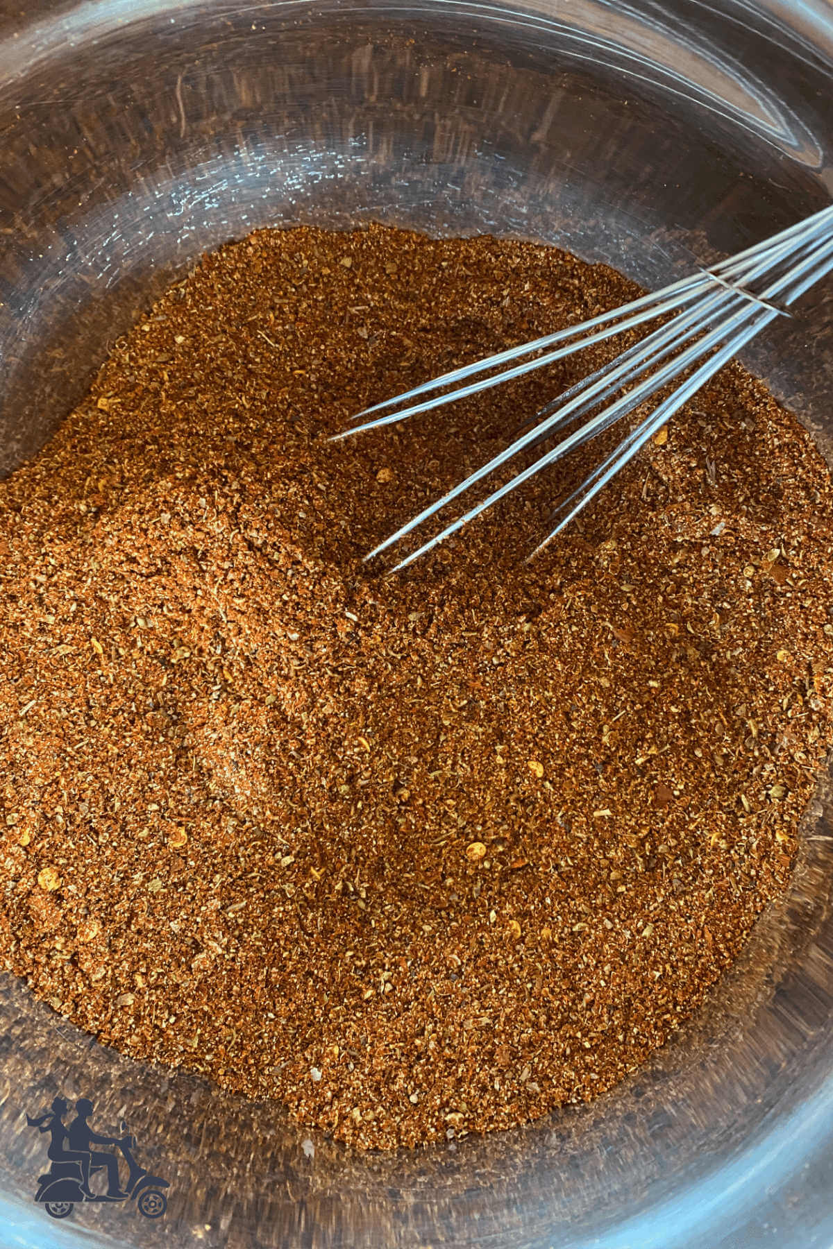 A metal bowl filled with the seasonings and a whisk with which to blend them.