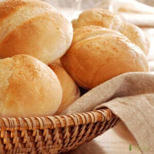 Italian hard rolls in a straw basket lined with a tan linen napkin.