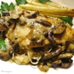 Chicken marsala with white asparagus on a white plate with parsley.