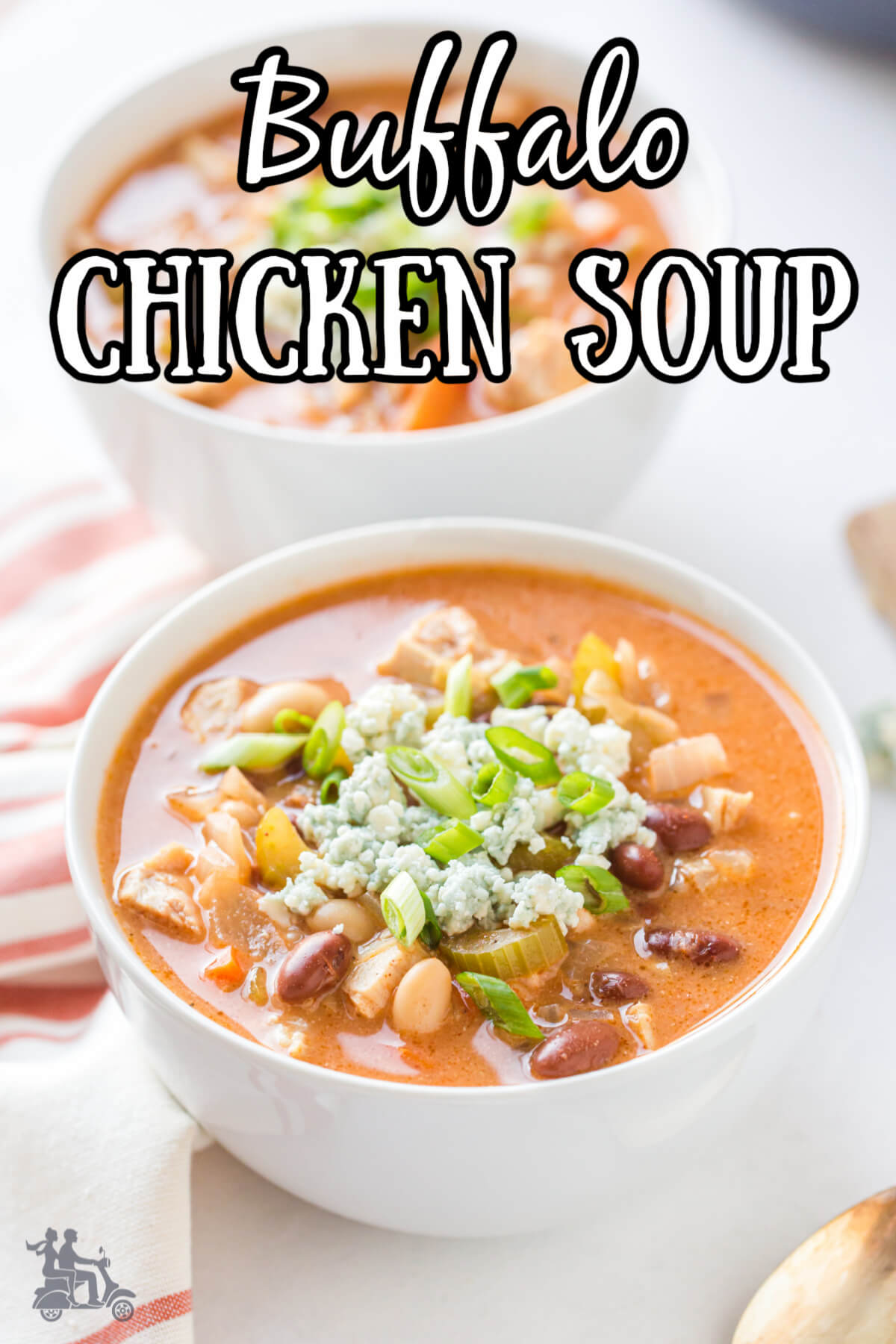 Two white bowls filled with Buffalo Chicken soup and garnished with bleu cheese and green onions. 