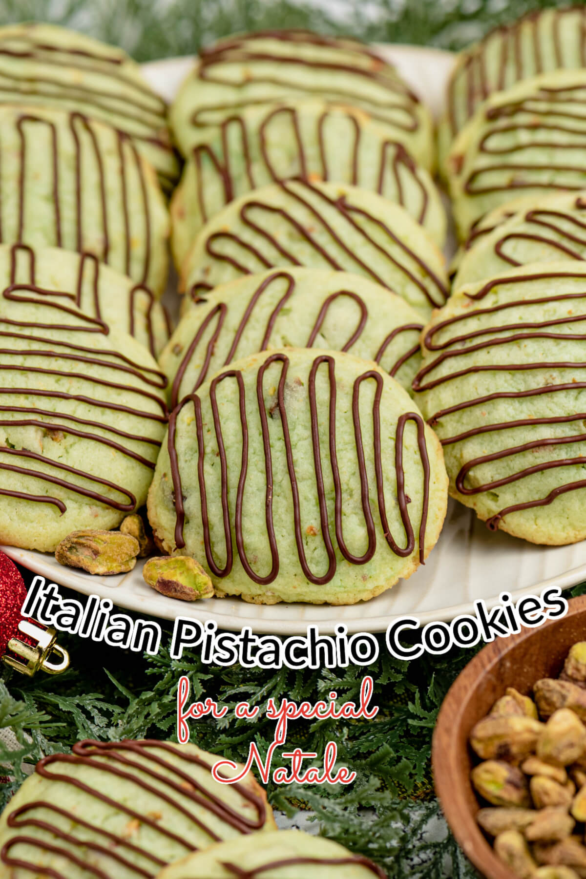 Pistachio cookies with Chocolate drizzle on top stacked on a white plate. 