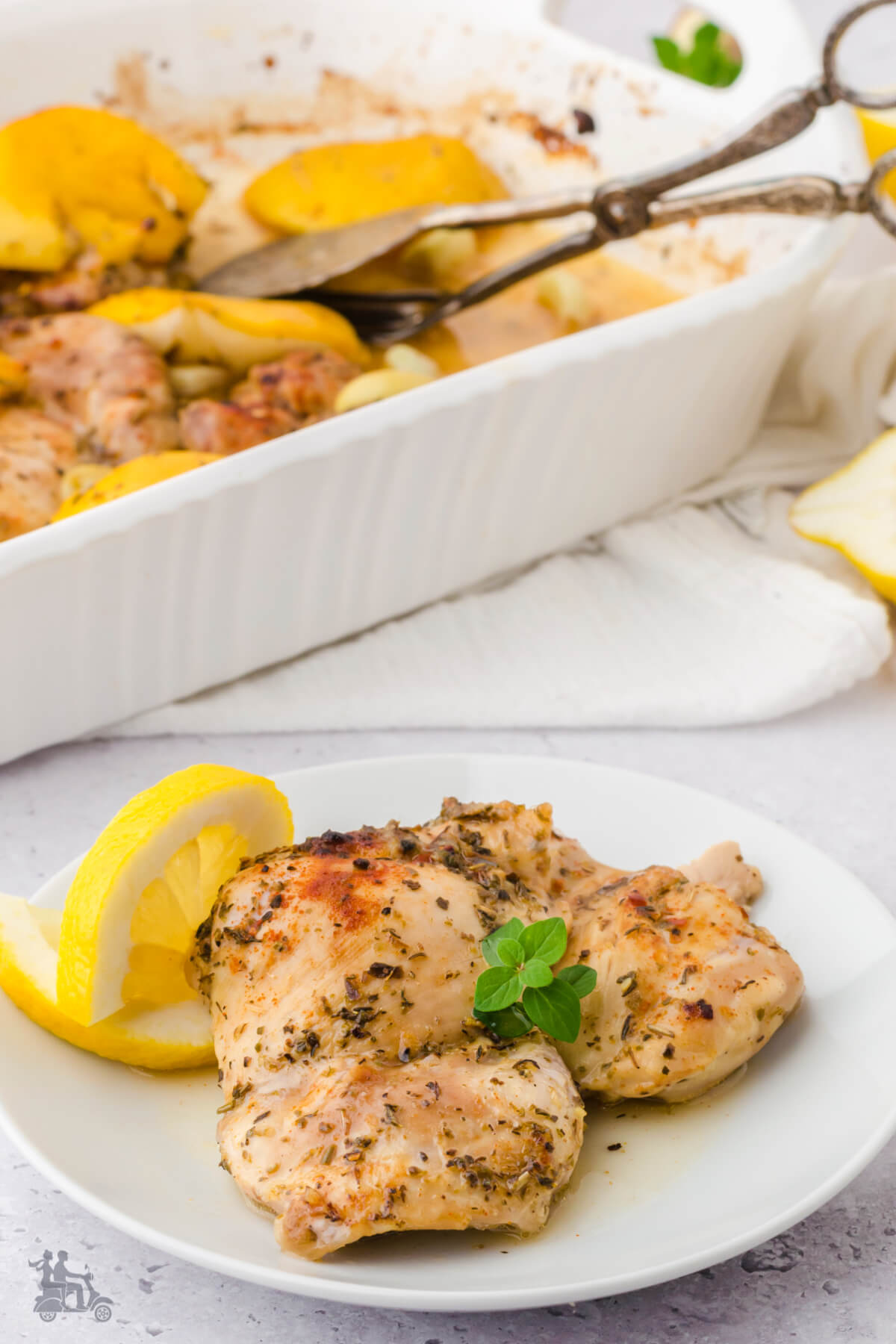 Roasted Lemon Garlic Chicken Thighs Casserole with a serving on a white plate. 