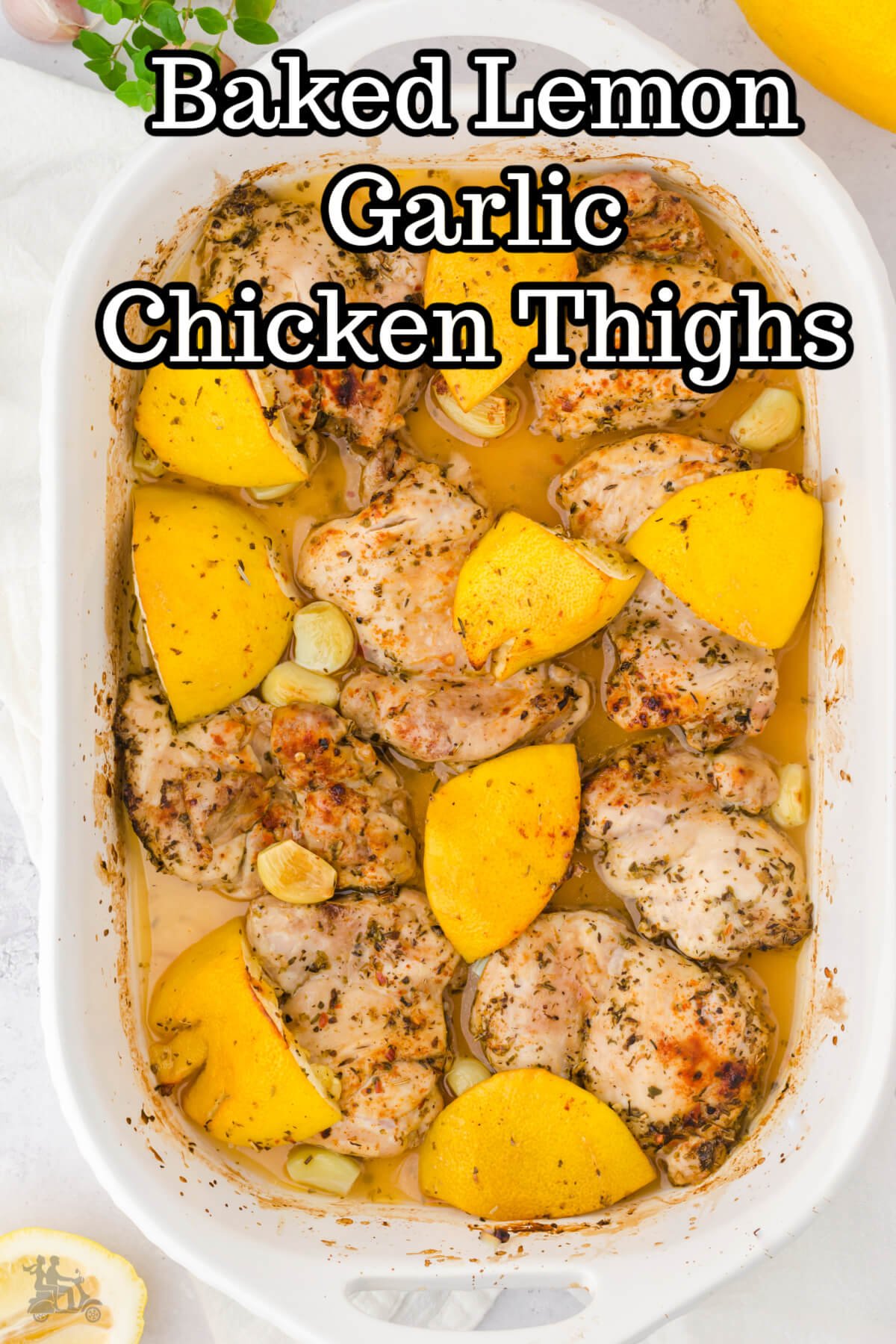 A white baking dish with  baked lemon garlic chicken thighs sprinkled with smoked paprika. 
