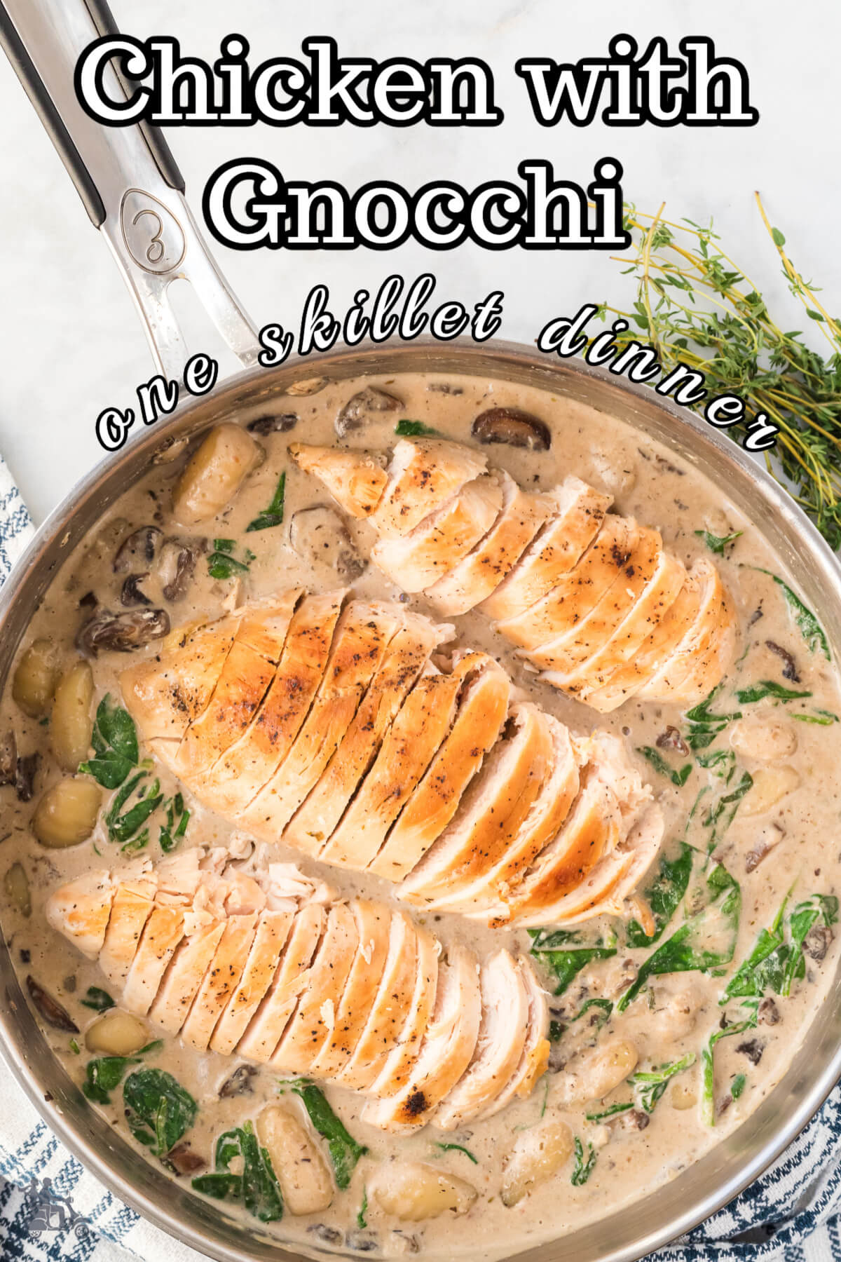 Skillet filled with a mushroom and gnocchi sauce and chicken breasts on top. 