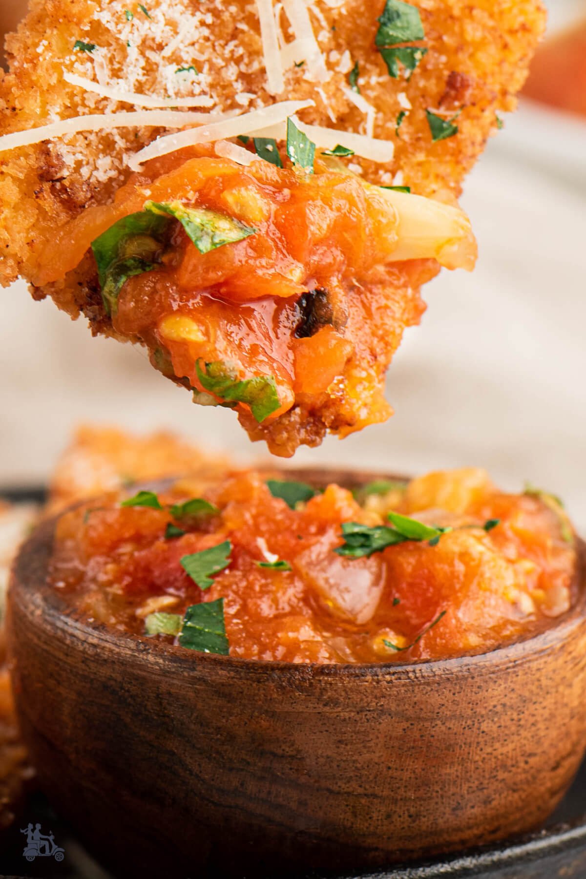 Close up of a fried ravioli with some tomato dipping sauce on the edge of it. 