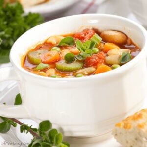 A bowl of vegetable soup in a white bowl. p