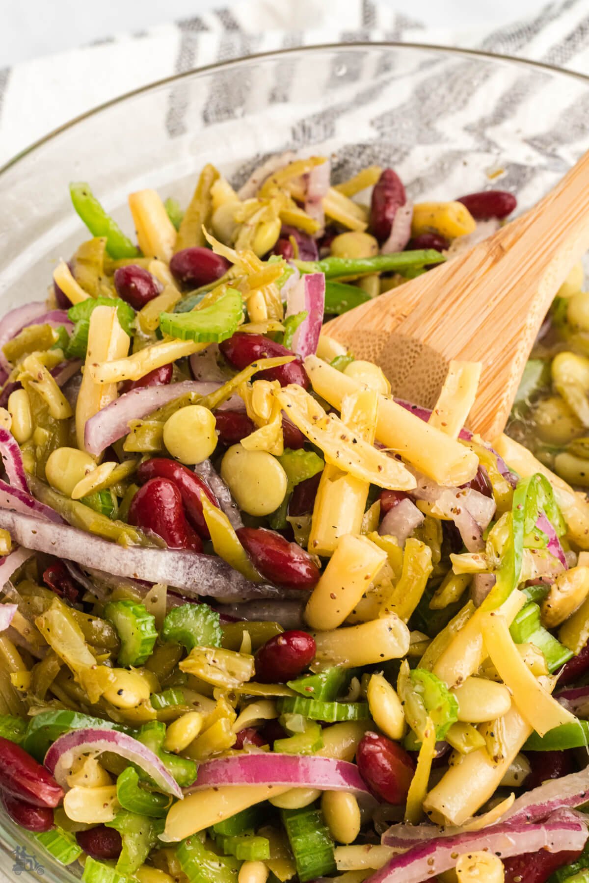 A wooden spoon ready to serve the bean salad. 