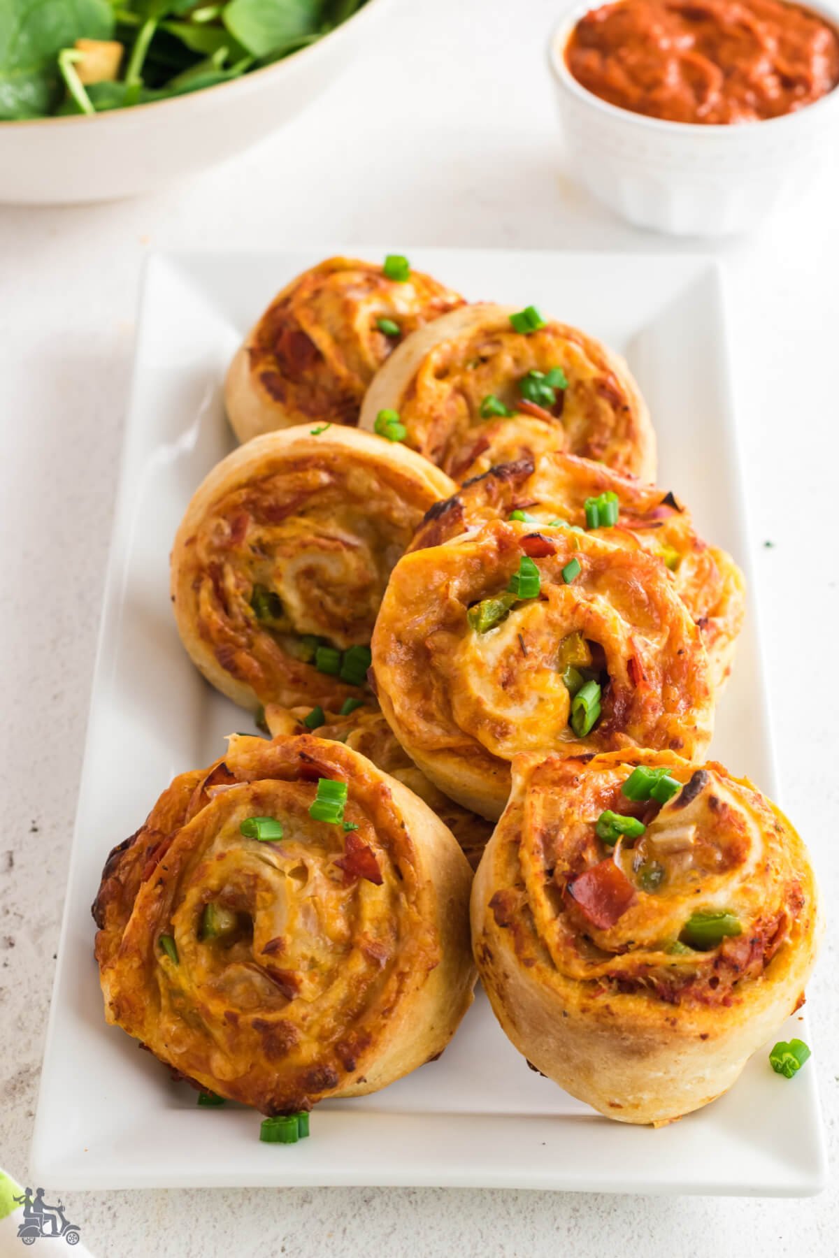 White platter with baked pinwheel pizza appetizers. 