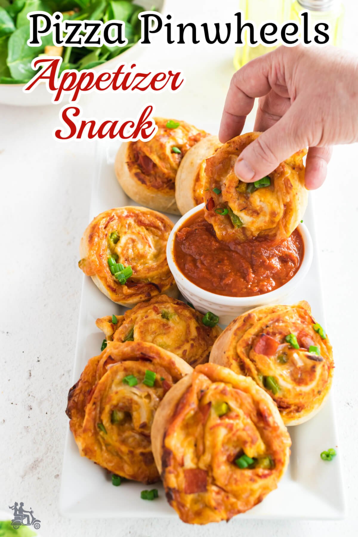 Hand dipping a baked dough spiral in marinara sauce. 