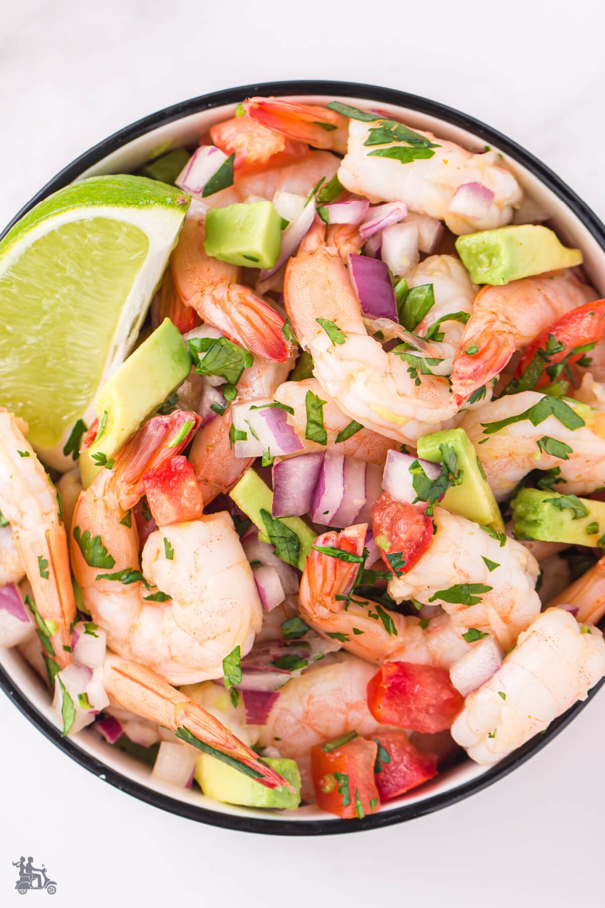 Overhead view of an appetizer recipe of shrimp, avocado, tomato, and cilantro.
