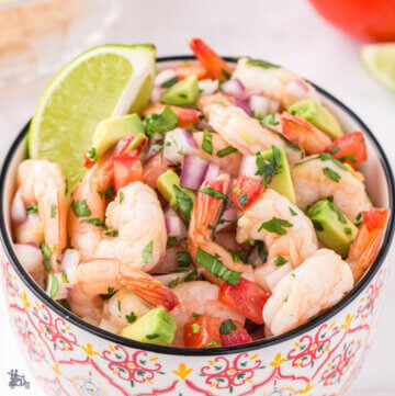 Bowl filled with shrimp ceviche with lime wedge.