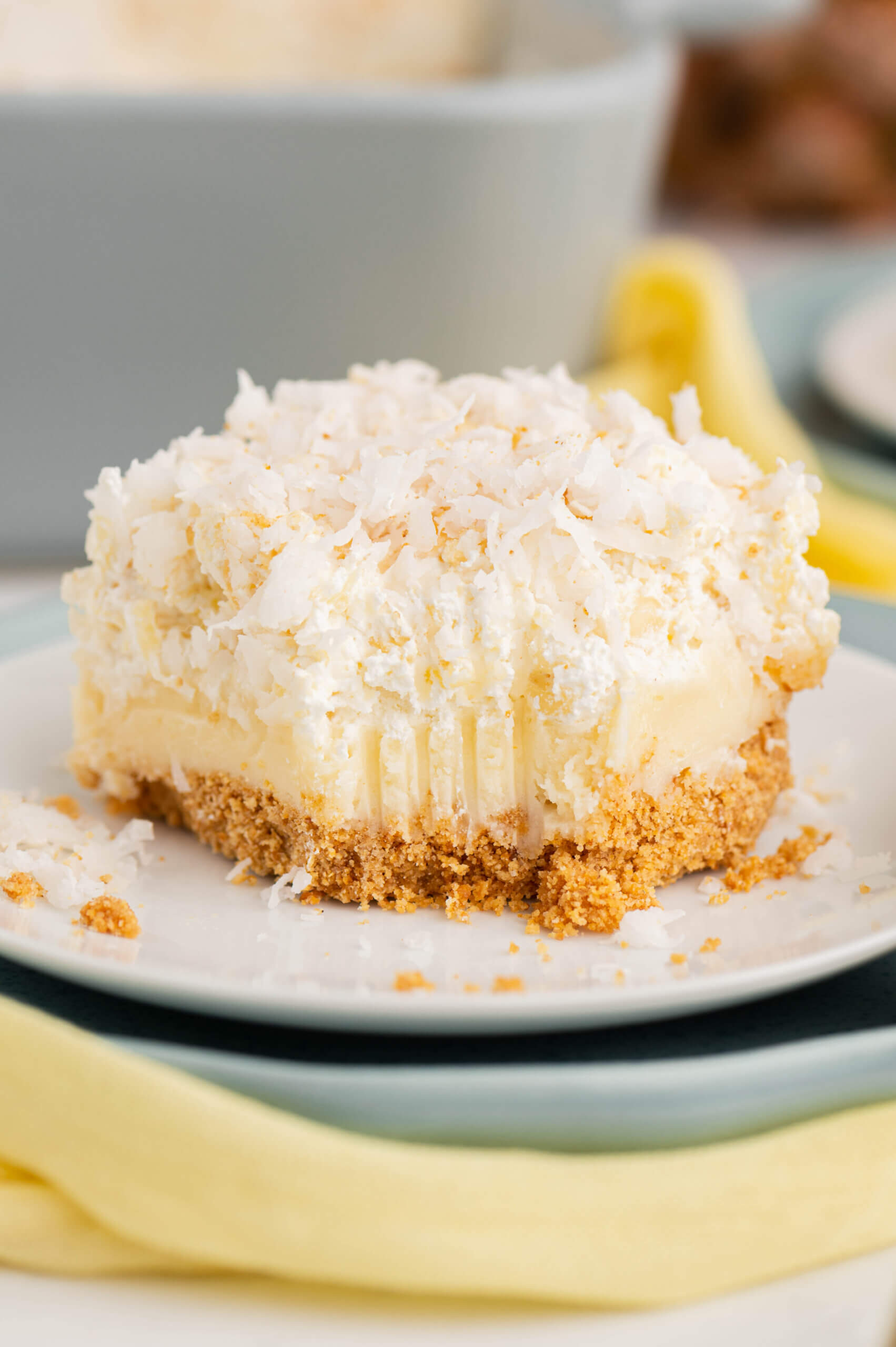 A serving of the pineapple cheesecake with coconut on a white plate. 