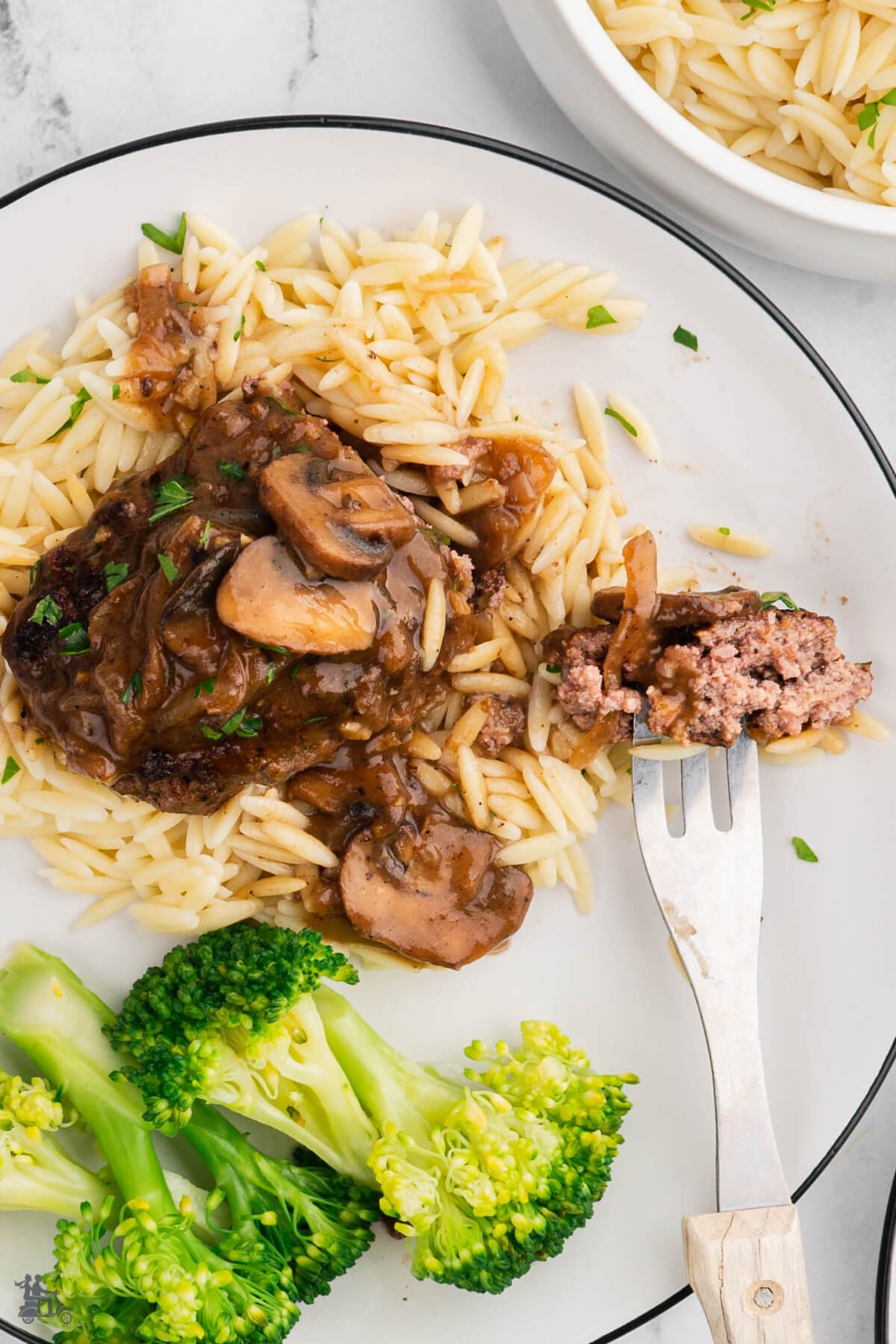 A fork with a bite of hamburger steak with mushroom gravy. 
