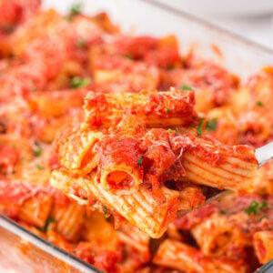 Cheesy rigatoni tubes covered with a marinara sauce in a casserole dish.