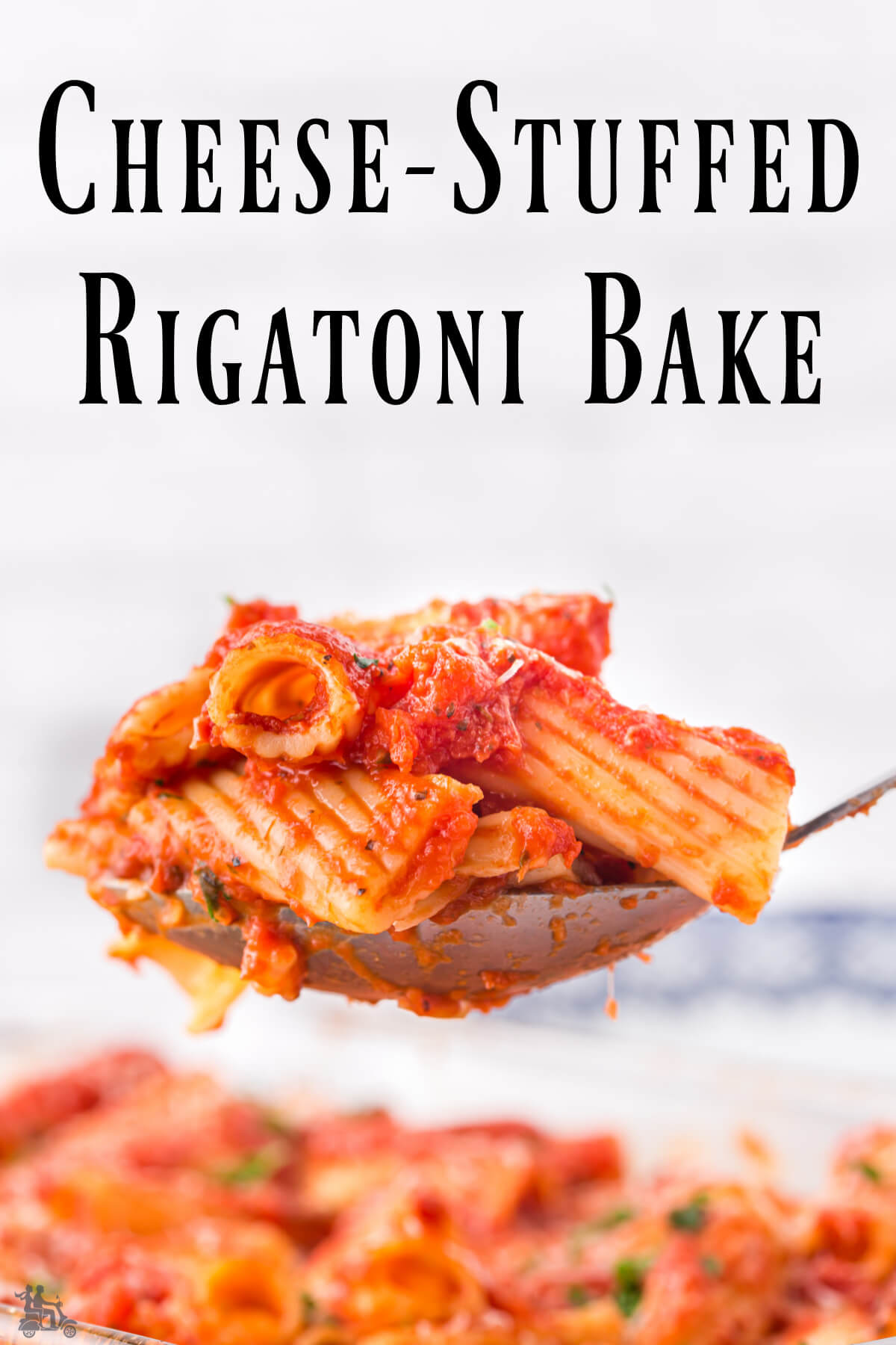 A serving spoon full of cheese stuffed baked rigatoni. 