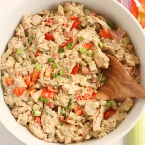 Chicken salad with wooden spoon in white bowl.