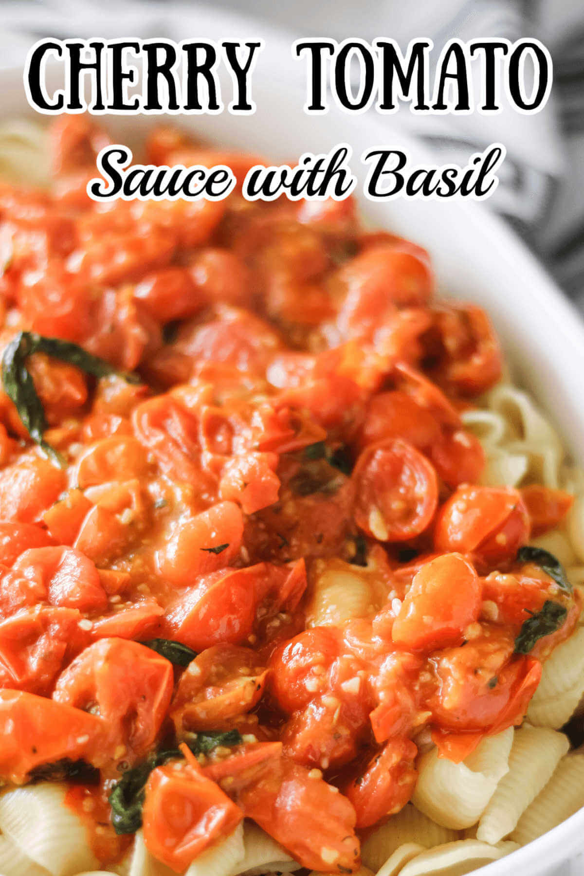 Cherry tomato sauce with basil on top of pasta in a white casserole dish. 