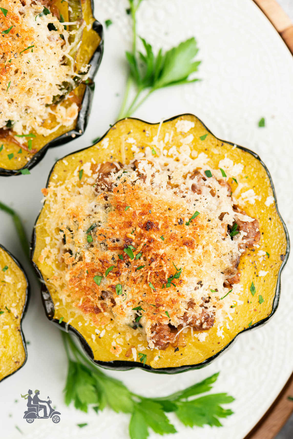 A platter with acorn squash halves that are stuffed with sausage and mushroom. 