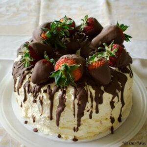 Cannoli Cake filled with sweetened ricotta cheese and chocolate chips and topped with whipped cream and chocolate-dipped strawberries.