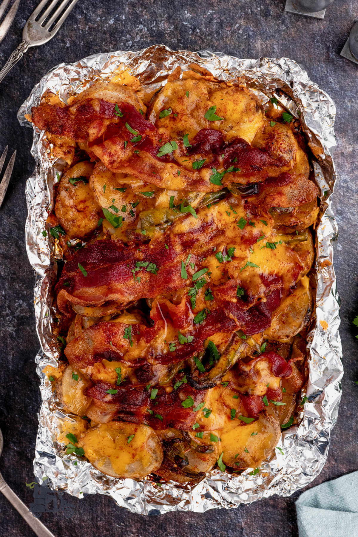 Cheesy grilled potatoes in foil packet with green peppers, onion, and bacon. 