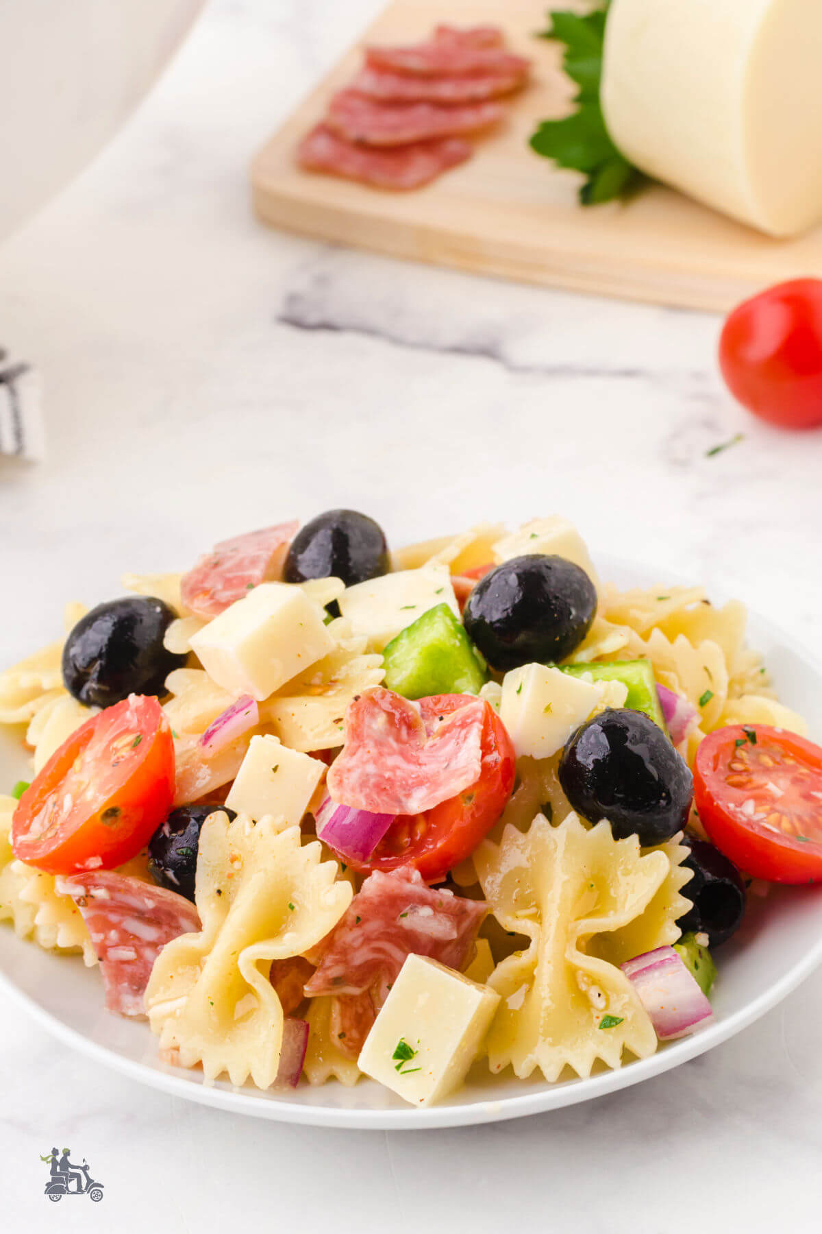 A bowl with Bow tie pasta salad with cheese and salami. 