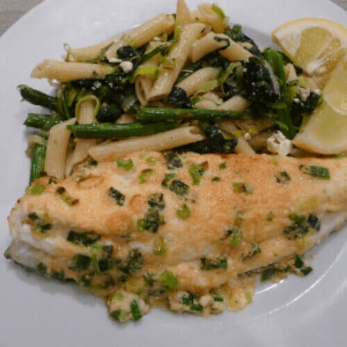 Parmesan broiled flounder on plate with pasta and spinach.