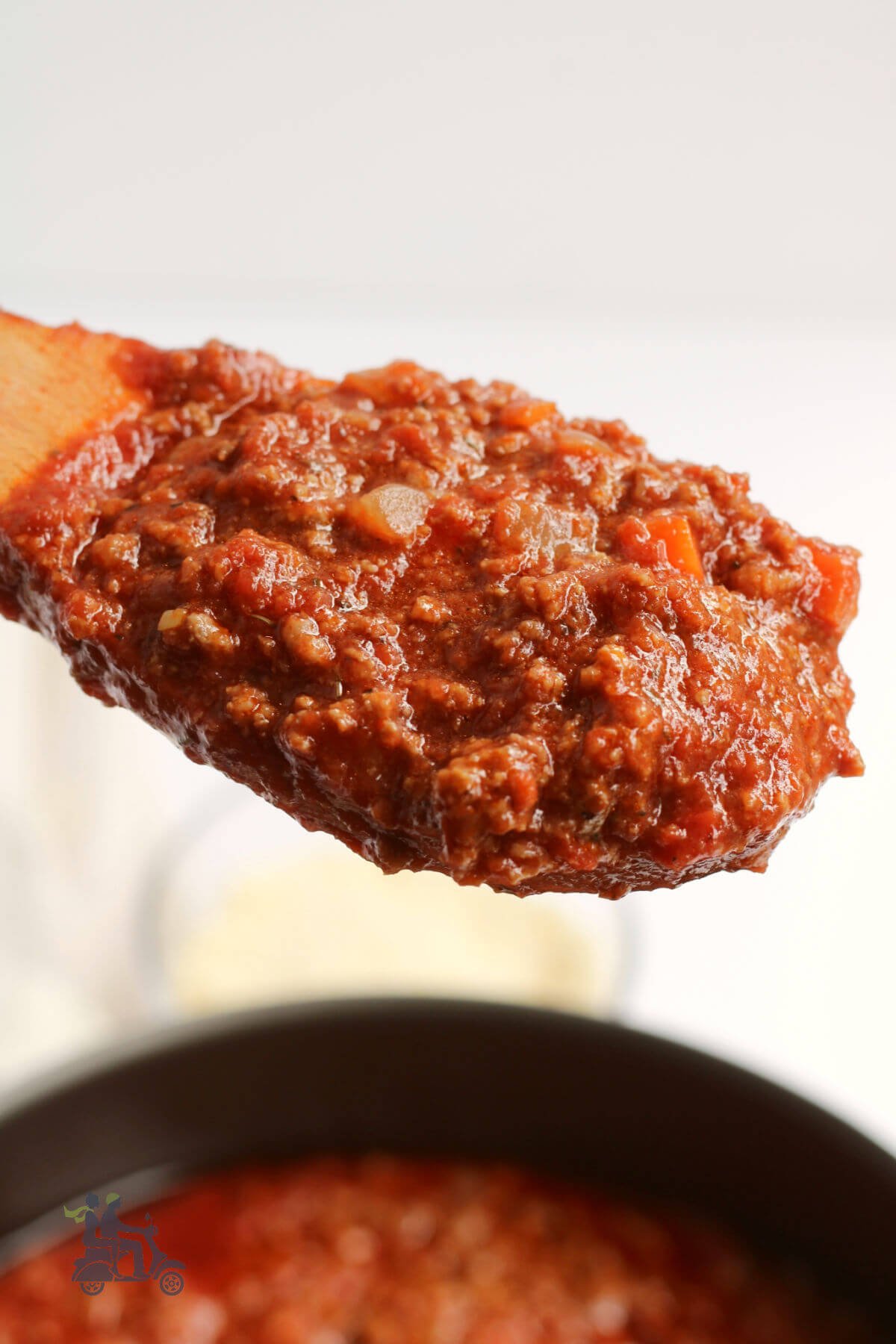 A wooden spoon holding the thick hearty Italian meat sauce. 
