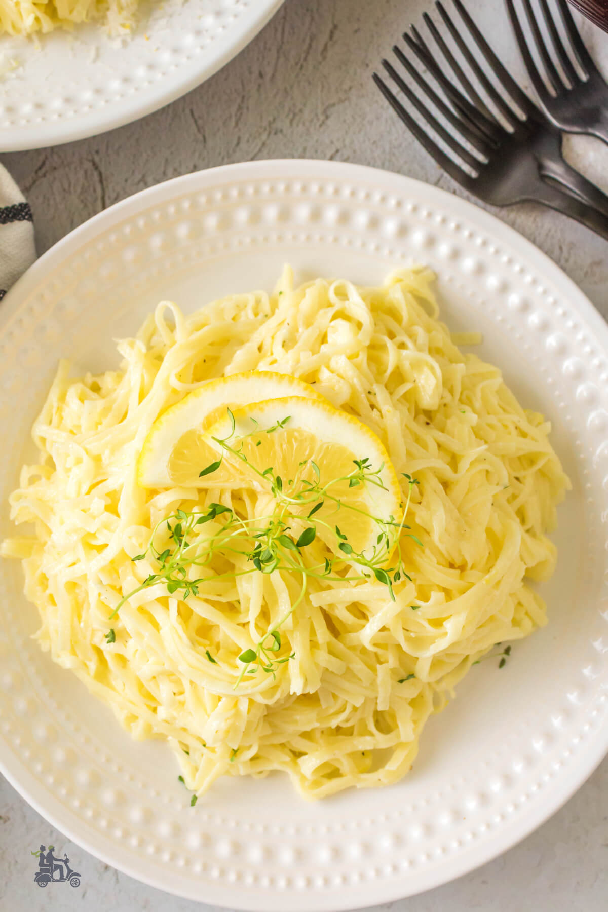 Pasta al limone with lemon wedge and thyme leaves on top. 