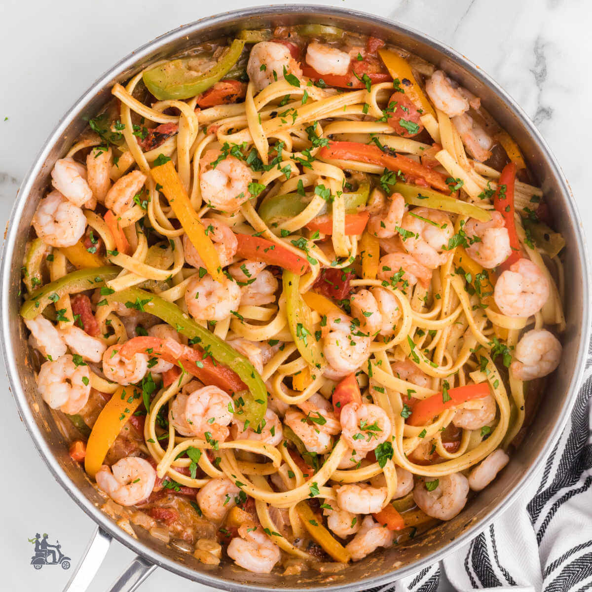 Shrimp rasta pasta in a large skillet comprising of colored peppers, shrimp, and pasta.