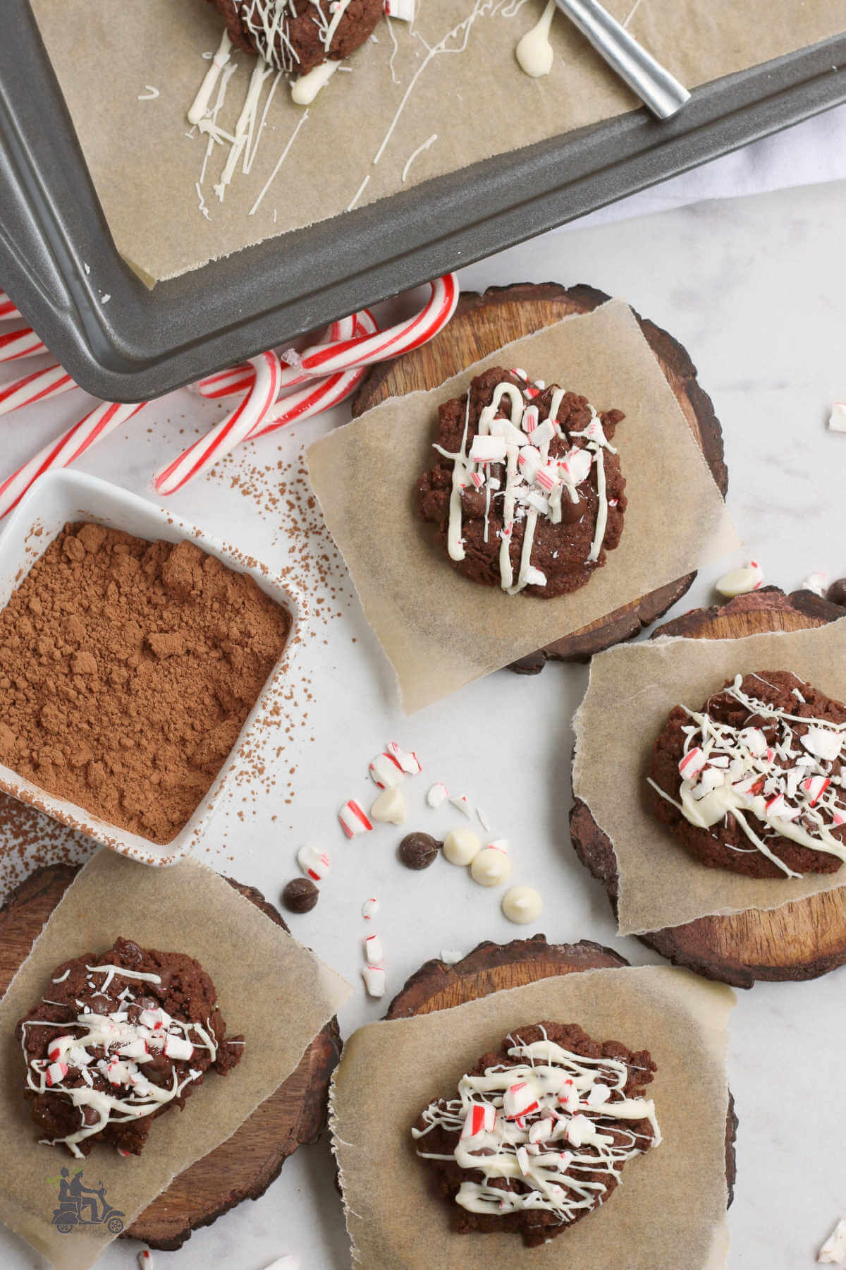 Chocolate cookies with white icing and peppermint sprinkles on top of wooden rounds with parchment paper. 