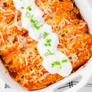 A white baking dish stuffed with cheese and sausage breakfast enchiladas.