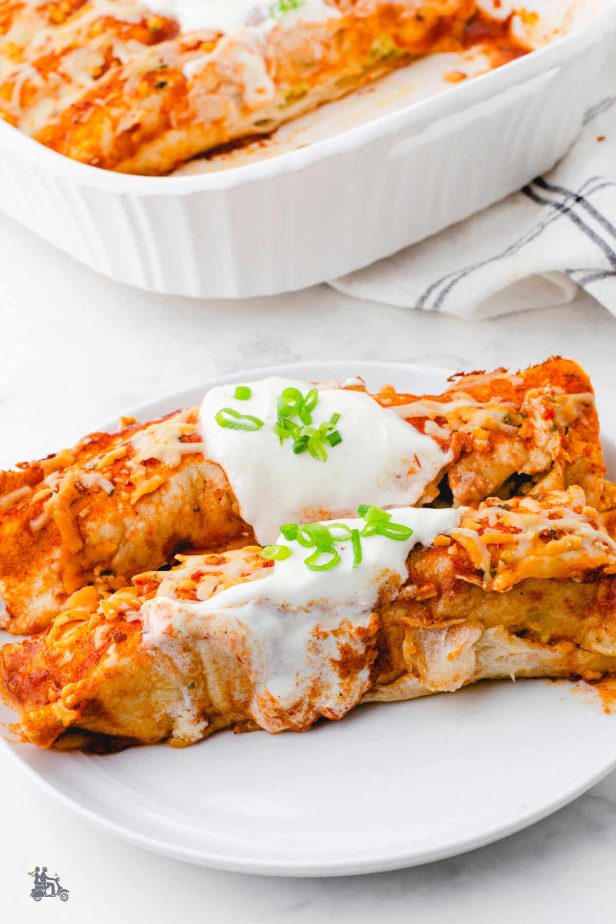 Two egg and sausage breakfast enchiladas on a white plate. 