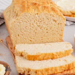 A no yeast sandwich bread load sliced on a cutting board with butter on the side.