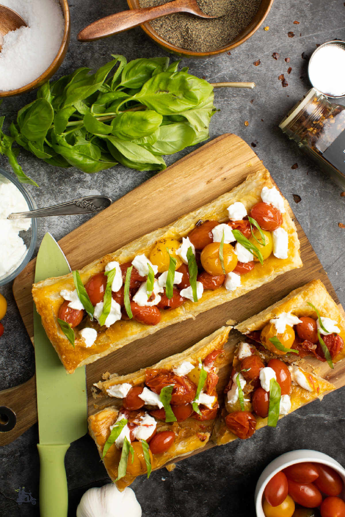Overhead view of puff pastry bruschetta pizza appetizer topped with grape tomatoes and goat cheese. 