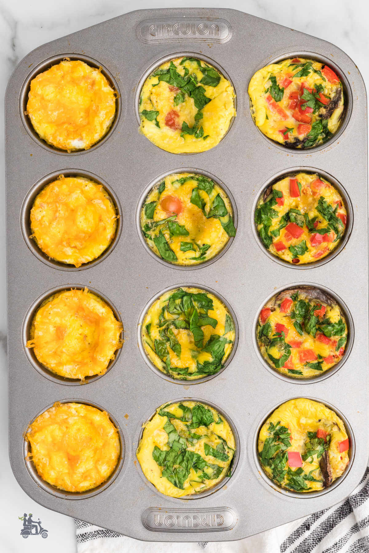 A muffin pan filled with three kinds of frittatas including bacon, spinach, red pepper, and cheese. 