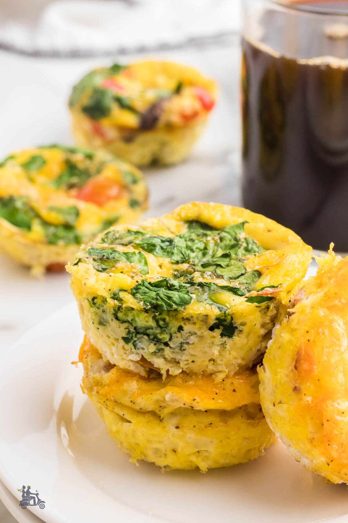 Breakfast table set with coffee, a white plate with egg muffins and more mini-frittatas in the background. 